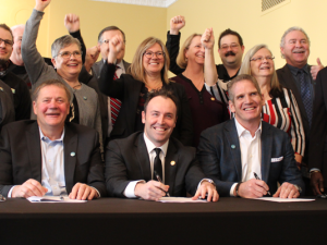 The mayors and reeves of JohnQ Public announce a new high-speed internet initiative. At the table: Macdonald Reeve Brad Erb, Chris Kennedy of RFNow Inc., and Rob Barlow of WireIE Inc.