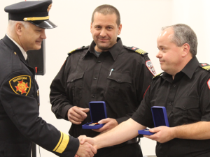 Fire Chief Scott Weir and Deputy Chief Paul Houle collect their service medals from Robert Pike, Manitoba’s Deputy Fire Commissioner.