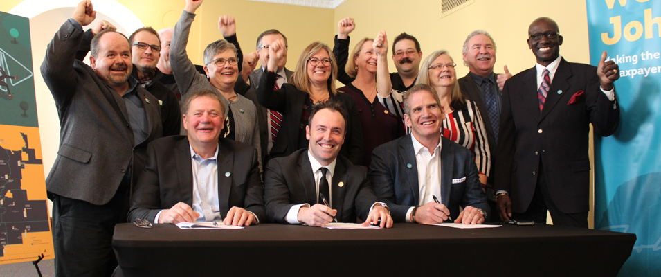The mayors and reeves of JohnQ Public announce a new high-speed internet initiative. At the table: Macdonald Reeve Brad Erb, Chris Kennedy of RFNow Inc., and Rob Barlow of WireIE Inc.