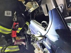 A Niverville firefighter using the jaws of life to open the dear door of a car.