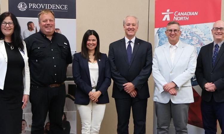Representatives from Providence University College, Harv’s Air Service, and Canadian North Airlines gather to witness the signing of their new partnership agreement.
