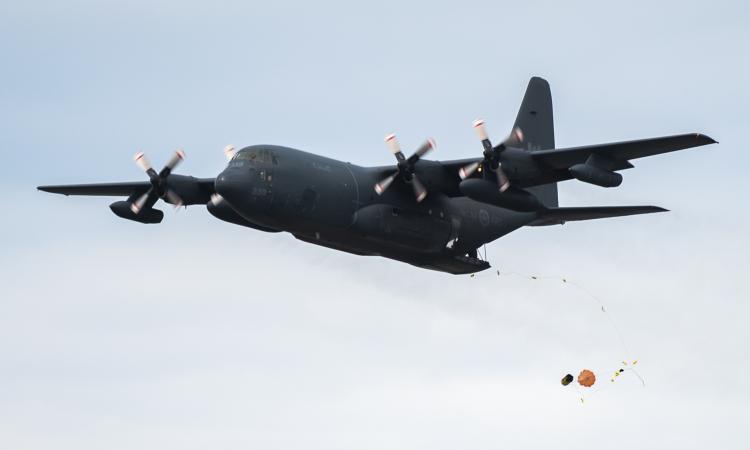 A CC-130 Hercules dispatches a survival raft during training on 25 July, 2022 over Lake Winnipeg in Gimli, Manitoba.