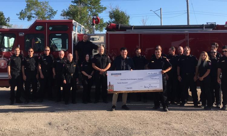 Greg Knox of Richardson International presents a donation cheque to Fire Chief Keith Bueckert.