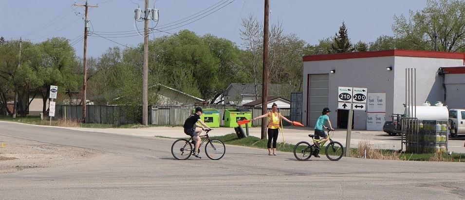 A crossing guard directs children through the intersection of Highways 200 and 201 in St. Adolphe.