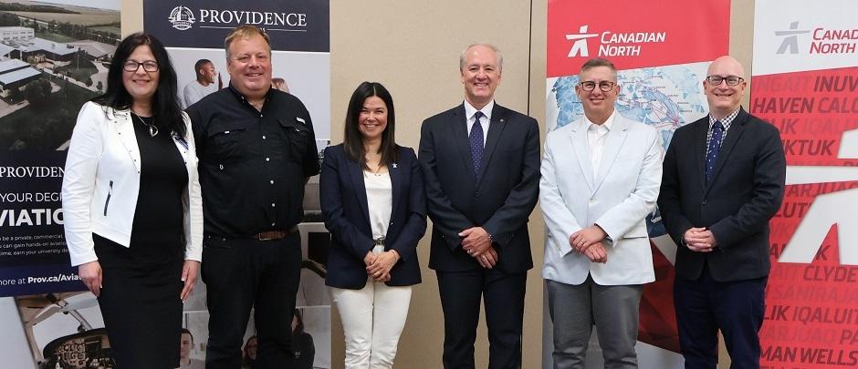 Representatives from Providence University College, Harv’s Air Service, and Canadian North Airlines gather to witness the signing of their new partnership agreement.
