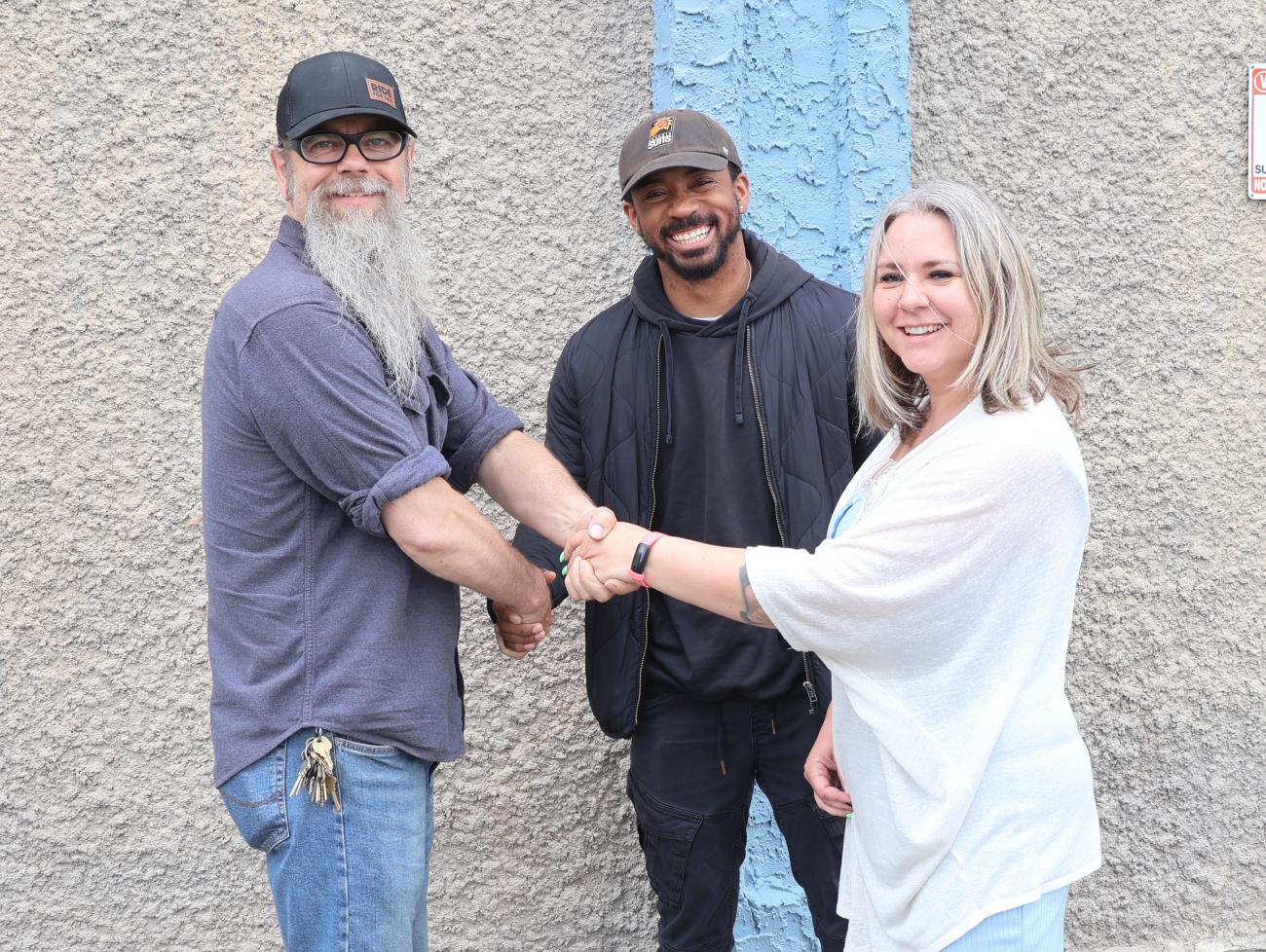 Entrepreneurs Tyree Milton-Gordon and Becky Nielsen shake hands with Troy Waldner, owner of 61 Main Street, which will be the site of their new rage room.