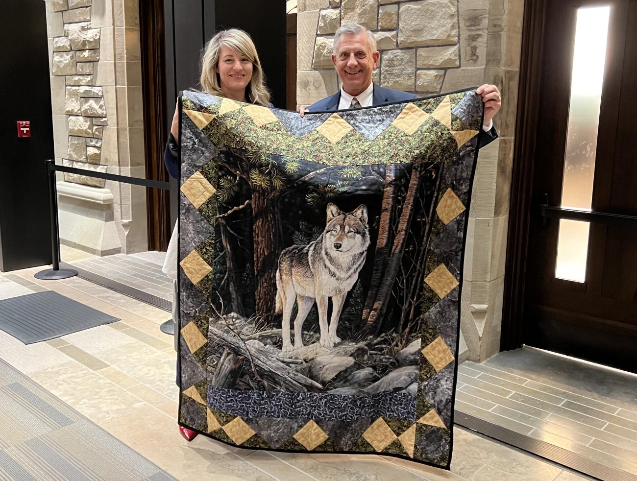 Mélanie Joly and Ted Falk hold the Zelensky quilt at the House of Commons in Ottawa.